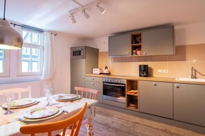 Eine kompakte Küche mit Essbereich, ausgestattet mit einem Tisch für zwei Personen, einer Mikrowelle, einem Toaster und einer Kaffeemaschine.