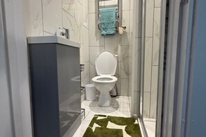 Une salle de bain comprenant des toilettes, un lavabo et un espace douche.