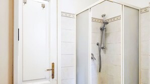 A bathroom with a shower, a white door, and a bathtub. - Lovely apartment for 2 people (Porlezza)