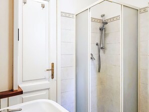 A bathroom with a shower, a white door, and a bathtub. - Beautiful apartment for 2 guests (Porlezza)