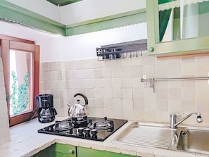 A compact kitchen with a gas stove, a kettle, a coffee maker, and a sink. - Cosy apartment for 2 guests (Porlezza)