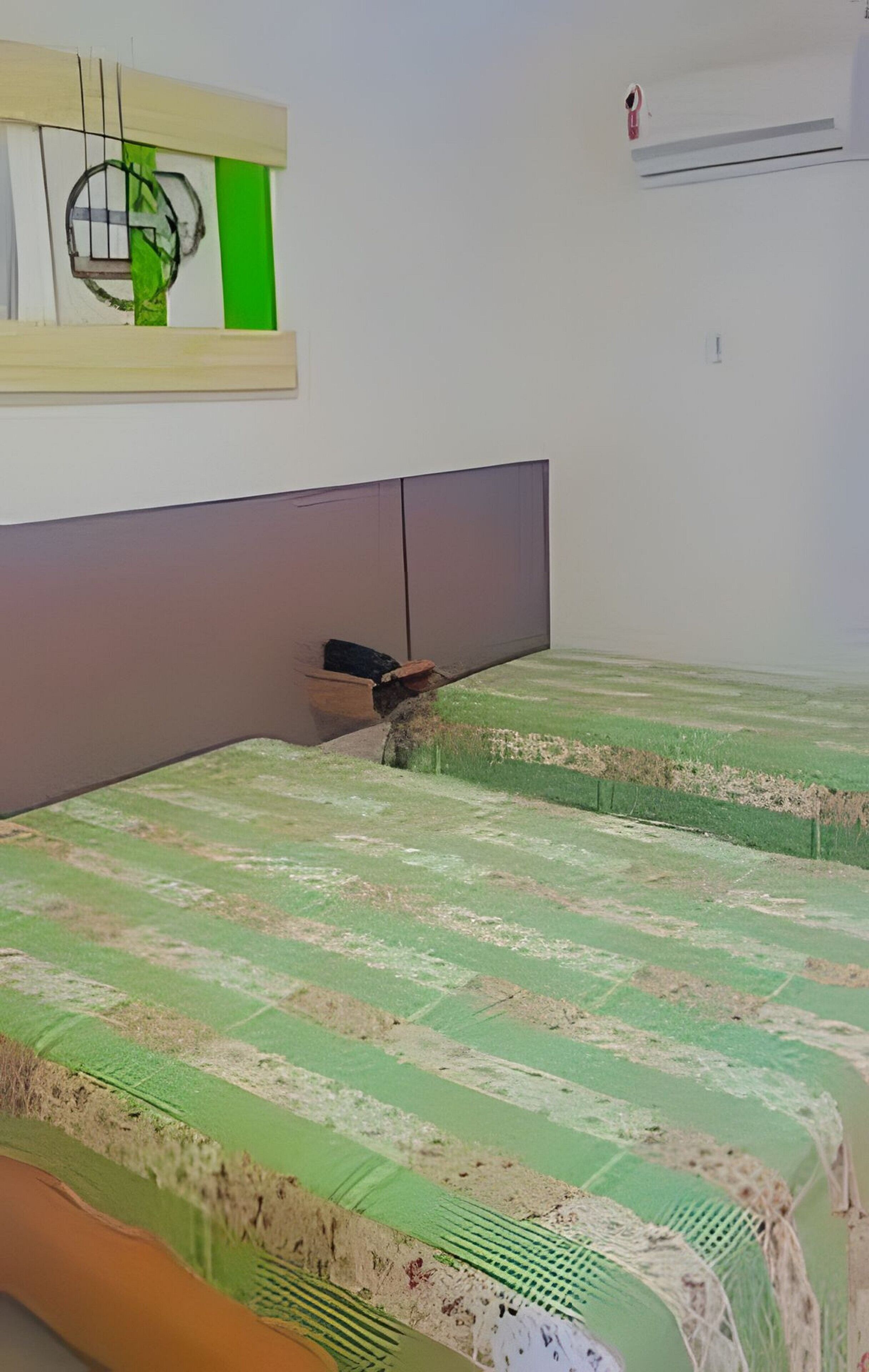A room with two beds, a headboard, a wall-mounted air conditioner, and a window.