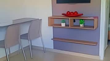 Uma sala de estar moderna com televisão de tela plana na parede, uma mesa de jantar com cadeiras e um pequeno aparador com objetos decorativos.