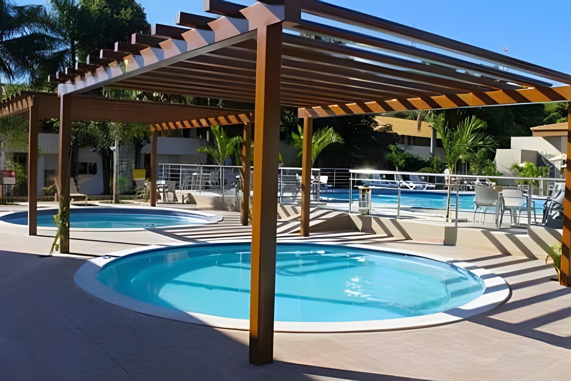 A pool area with two circular pools, a pergola, and lounge chairs.