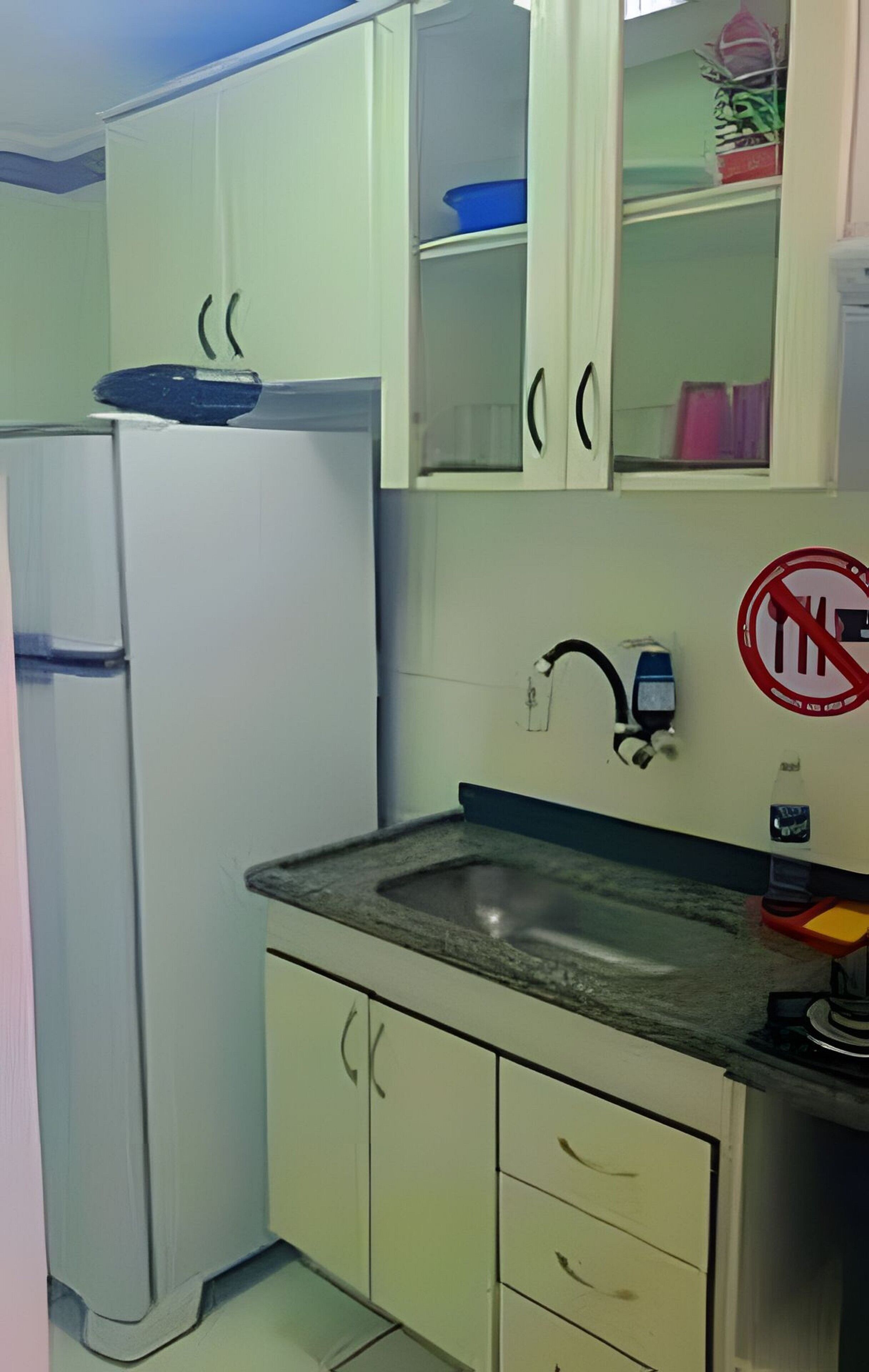 Eine kleine Küche mit einem weißen Kühlschrank, einer Spüle und Schränken.