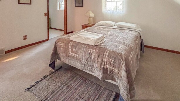 Un dormitorio con una cama, una mesita de noche, una ventana y una puerta.