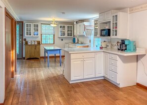 A kitchen with white cabinets, a blue table, and a wooden floor.