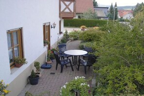 A patio with a round table and chairs, surrounded by potted plants and a hedge. - Holiday apartment with 1 bedroom (St. Peter)