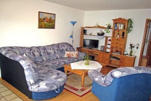 A living room with a sofa, armchair, coffee table, TV, and wooden cabinet. - Holiday apartment with 1 bedroom (St. Peter)