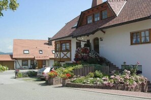 A traditional house with a sloped roof, a front porch, and a garden with flowers. - Holiday apartment with 1 bedroom (St. Peter)