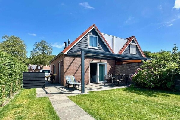 Ein zweistöckiges Haus mit überdachter Veranda, Ziegelaußenwand und blauem Himmel.
