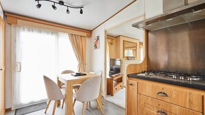 A compact kitchen with a stove, cabinets, and a dining area with chairs and a table.