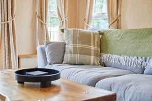 Ein gemütliches Wohnzimmer mit einer Couch, Kissen und einem Couchtisch.