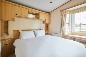 A bedroom with a bed, wooden cabinets, a window with curtains, and a radiator.