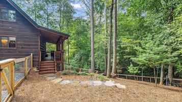 A wooden cabin with a deck and a fenced yard.