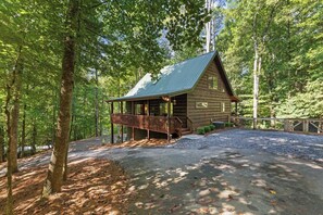 Une cabane dotée d’une véranda, entourée d’arbres.