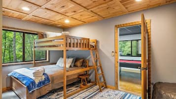 A bunk bed with a ladder, a window with a view of trees, and a patterned rug.