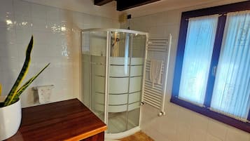 Une salle de bain avec une douche à parois de verre, un meuble-lavabo en bois et une fenêtre avec des rideaux.