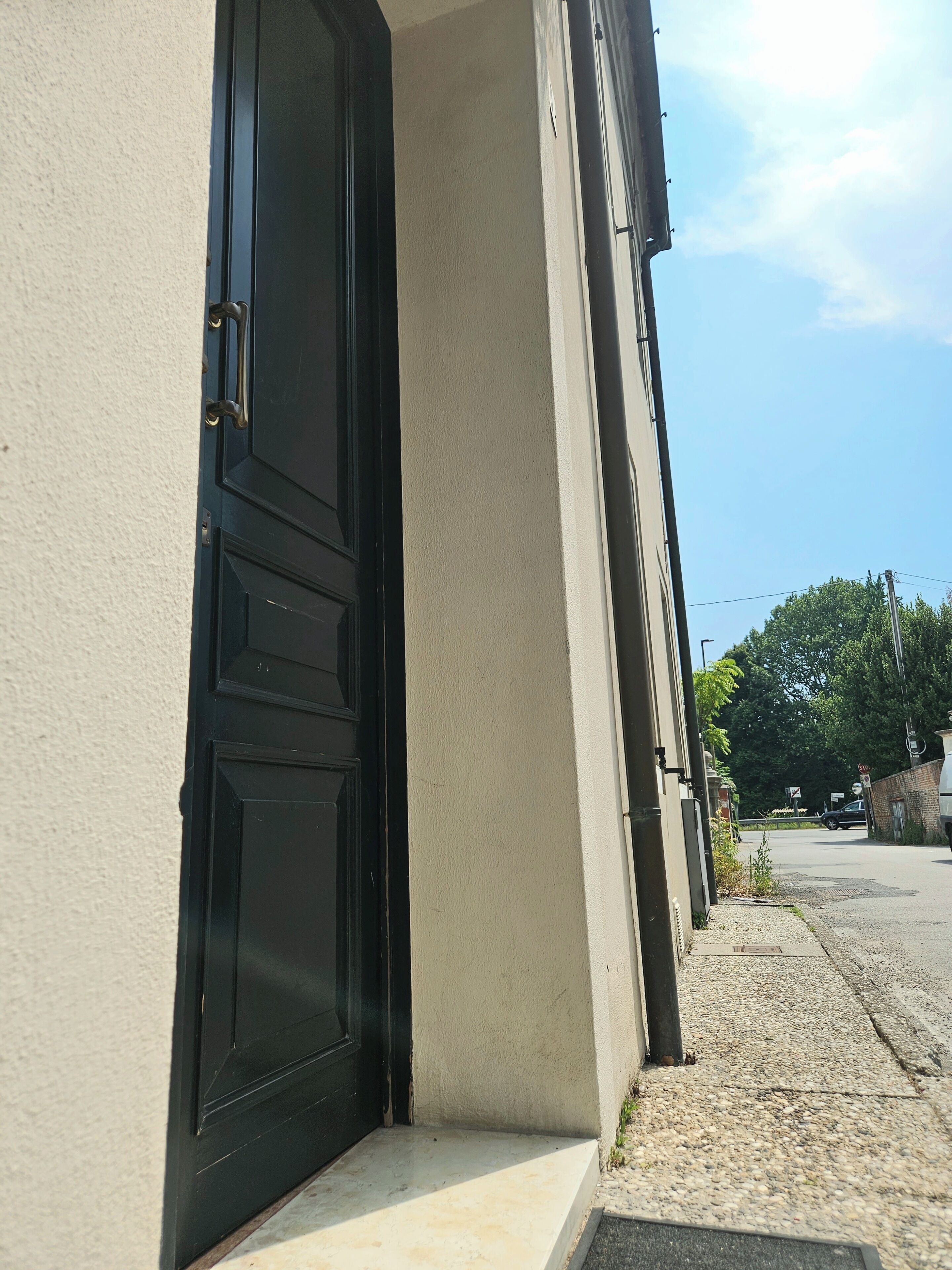 Un bâtiment avec une porte noire, des murs de couleur beige et un ciel dégagé.