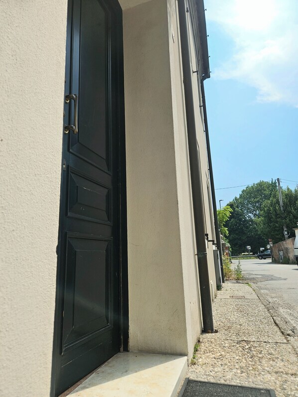 Un edificio con puerta negra, paredes color beige y cielo despejado.