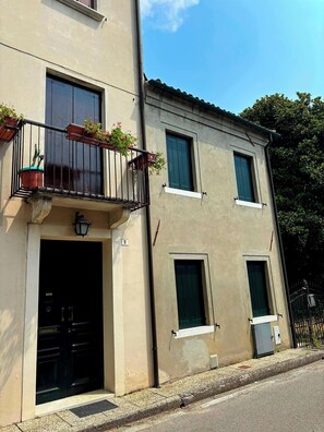 A two-story building with a balcony, a door, and windows.