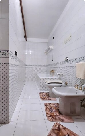 A bathroom with white tiled walls, a toilet, a bidet, and a sink. - Antica Dimora Confine (Mira)