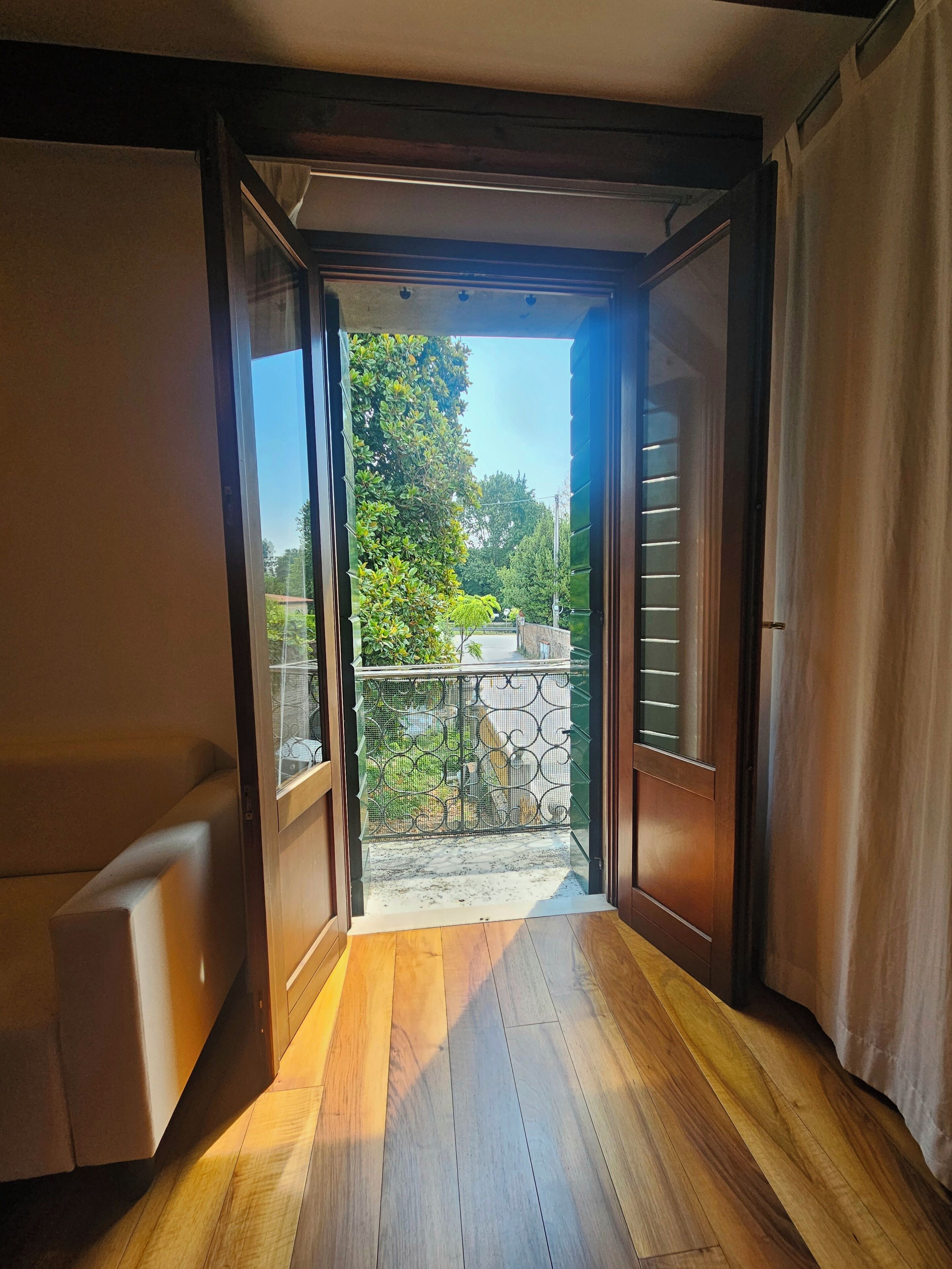 Une porte coulissante ouverte donne accès à un balcon d’où l’on peut admirer la verdure et un mur en pierre.