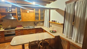 Una cuina amb armaris de fusta, un taulell de marbre i una zona de dinar amb caires.