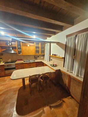Una cocina con armarios de madera, encimera de mármol y comedor con sillas.