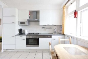 Uma cozinha moderna com armários brancos, fogão a gás, forno, micro-ondas e pia.