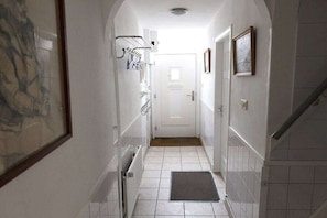 A narrow hallway with a door at the end, a radiator on the left, and a mat at the entrance. - Holiday home in Domburg with swimming pool (domburg)