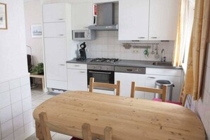 A compact kitchen with white cabinets, a microwave, a gas stove, and a sink. - Holiday home in Domburg with swimming pool (domburg)
