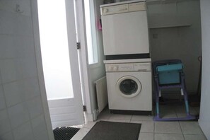 Uma lavanderia com máquina de lavar, secadora e mesa para dobrar roupa.