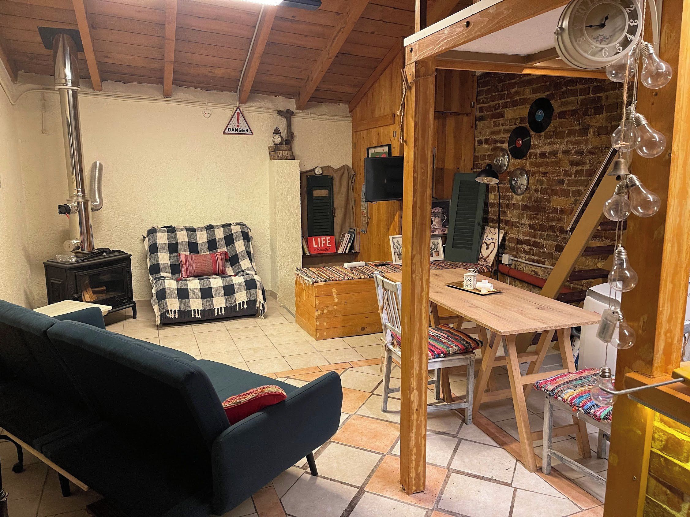 Ein gemütliches Zimmer mit Holzbalkendecke, einer Couch, einem Tisch mit Stühlen und einem Kamin.
