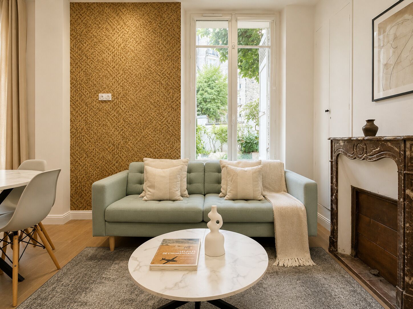 A living room with a sofa, a coffee table, a fireplace, and a window with a view of greenery.