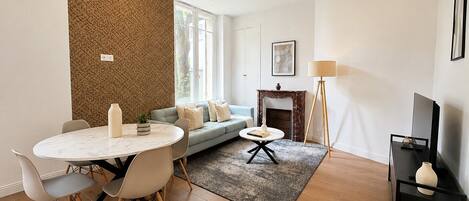 A modern living room with a dining area, a fireplace, and a television.
