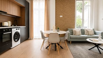 A modern kitchen with appliances, a dining area with a table and chairs, and a living area with a sofa and a coffee table.