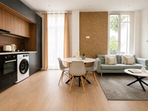 A modern kitchen with appliances, a dining area with a table and chairs, and a living area with a sofa and a coffee table.