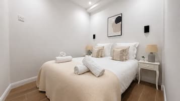 Ein Schlafzimmer mit einem großen Bett, zwei Nachttischen, einer Wandleuchte und einem gerahmten Kunstwerk.