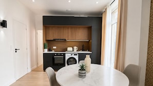Cozinha moderna equipada com forno embutido, máquina de lavar e área de refeições com mesa redonda e cadeiras.