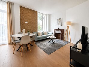 A modern living room with a dining area, a fireplace, and a television.