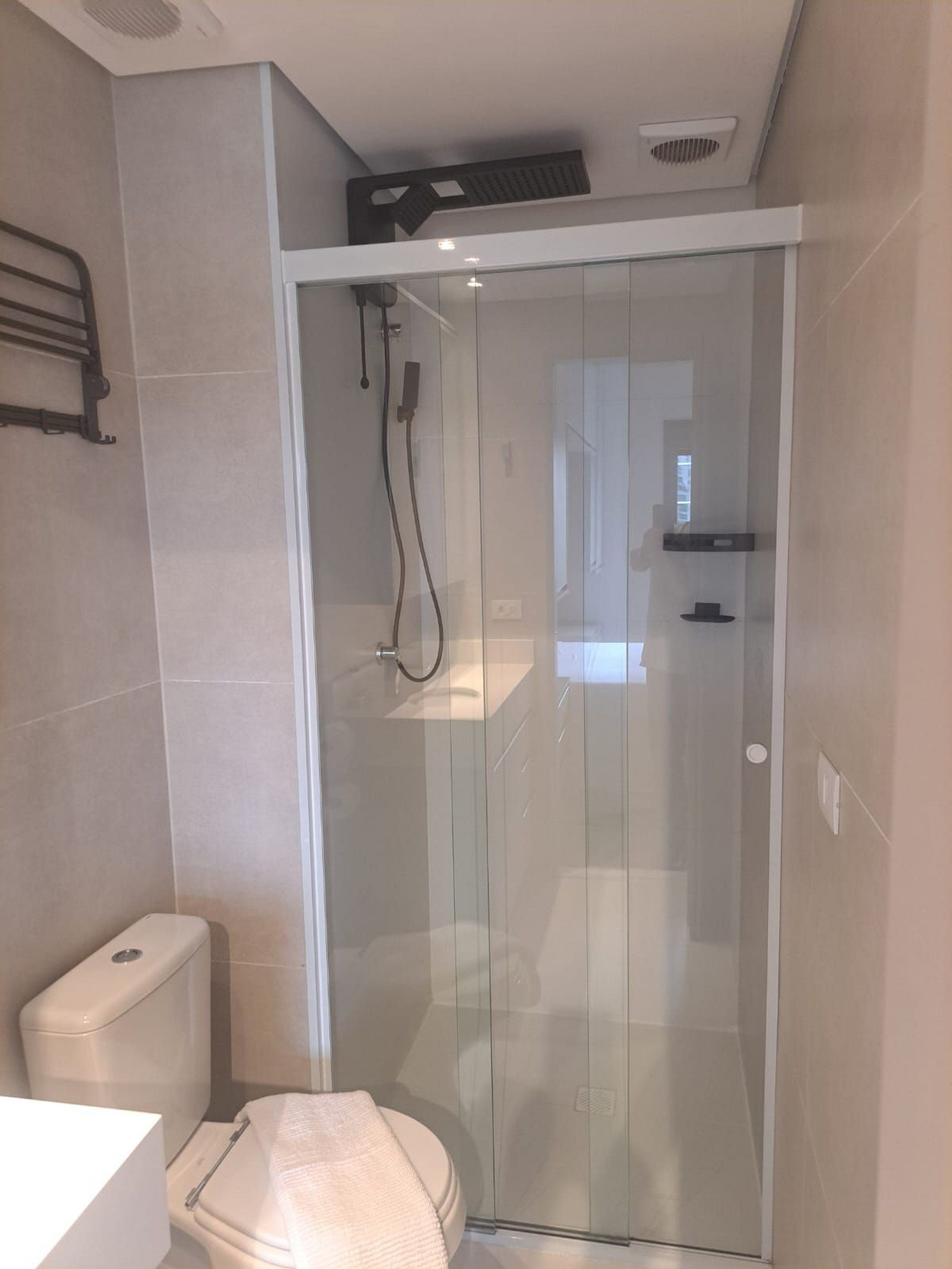 Een moderne badkamer met een douchecabine van glas, een toilet en een wastafel.