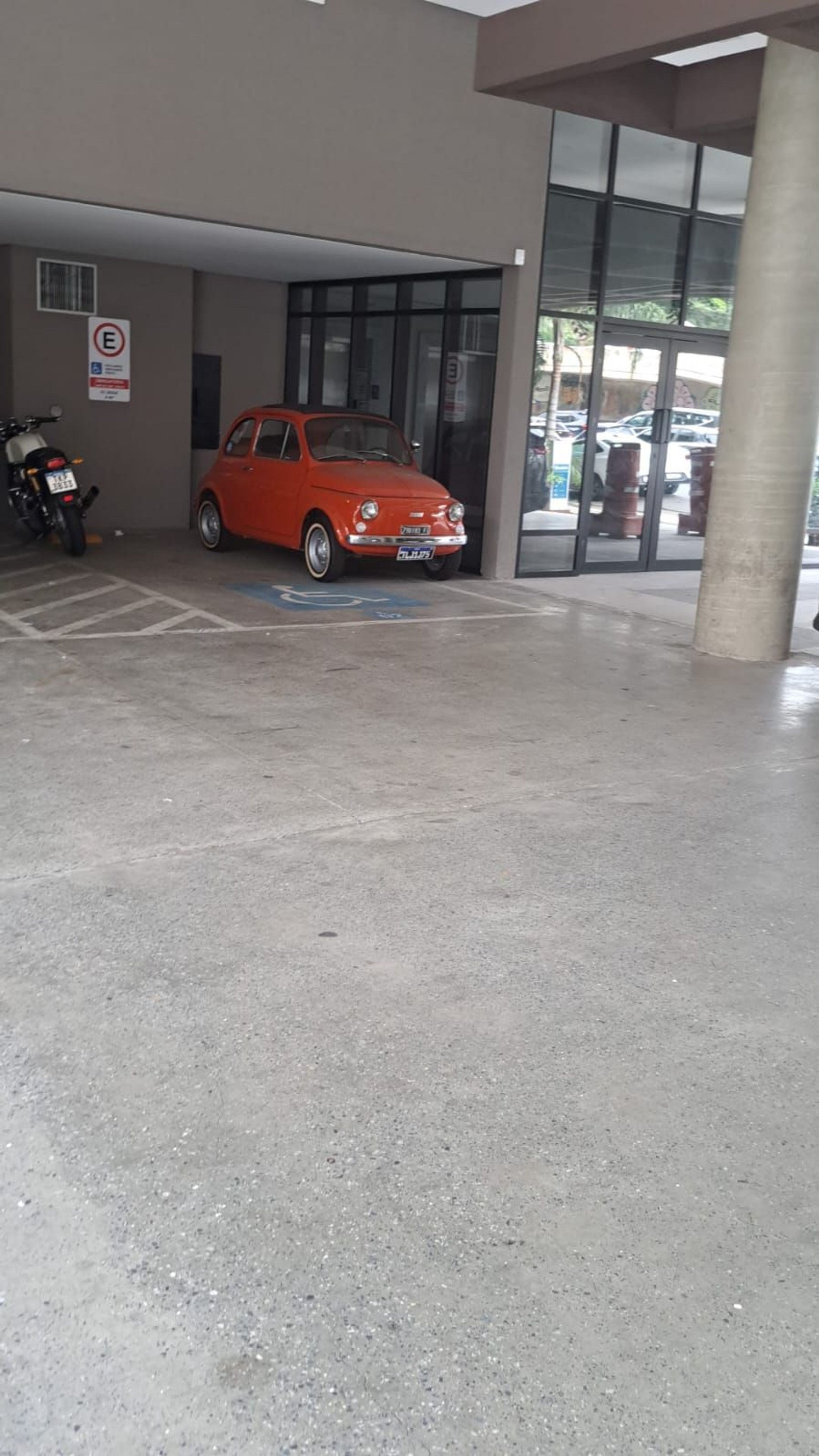Un área de estacionamiento con un auto rojo y una motocicleta.