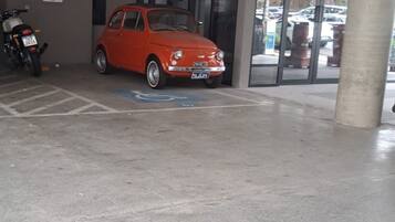 Un área de estacionamiento con un auto rojo y una motocicleta.