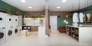 A modern laundry room with multiple washing machines, a sink, and a countertop with plants and towels.