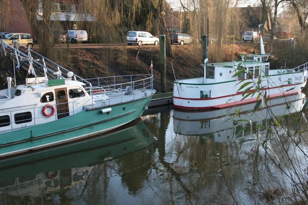 Two boats docked at a pier with a river in the background.