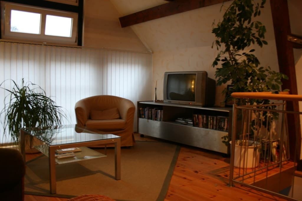 A living room with a sofa, a coffee table, a television, and a bookshelf.