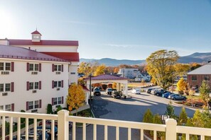 A multi-story building with a red roof, a covered parking area, and autumn foliage. - Lincoln NH | Ski Town Stay | Pool & Mountain Access (Lincoln)