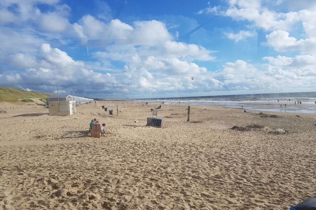 A sandy beach with a few structures, including a small shelter and a wooden bench.