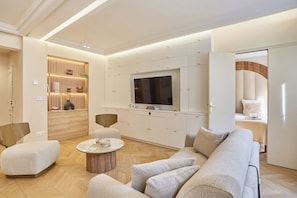 A modern living room with a sofa, armchairs, a coffee table, and a TV. - Beautiful air-conditioned apartment in Le Marais (Paris)